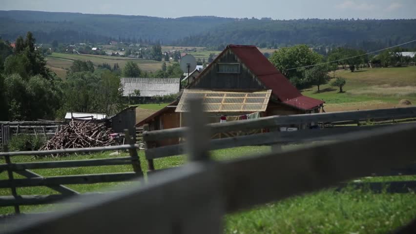 Country side house of the village in the valley, camera panning behind the wooden fence.