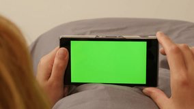 Woman in bed surfing through internet pages on green screen mobile 4K 2160p UltraHD footage - Female on greenscreen phone display 4K 3840X2160 UHD video