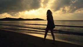 Young beautiful blonde woman silhouette walk on shore at sunset in summer outdoor - gimbal steadicam HD video footage