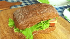 Delicious Sandwich of Rye Bread with Tomatoes, Lettuce, Sturgeon, Cheese and Spices on a table. Full HD 1920x1080 Video Clip