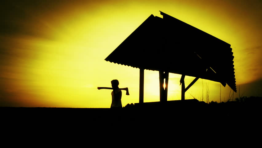 Silhouette of a boy on sunset at the old well. Silhouette of a child in a field at sunset. Teen boy with the tool on nature. Nature, child, silhouette, sunset.