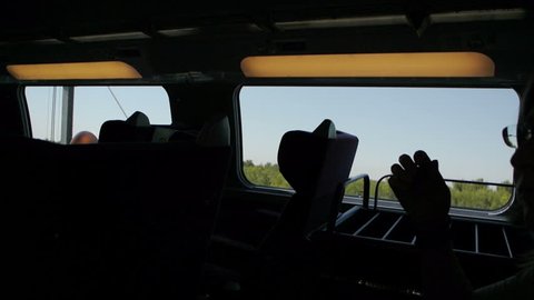 Silhouette of a woman traveling by fast train with green forest and field seen through the window