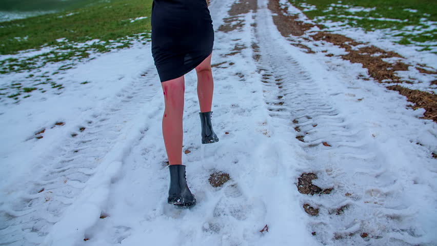 Running away in snow. Girl running over the filed covered with snow away from kidnapper in a countryside, footage in slow motion.
