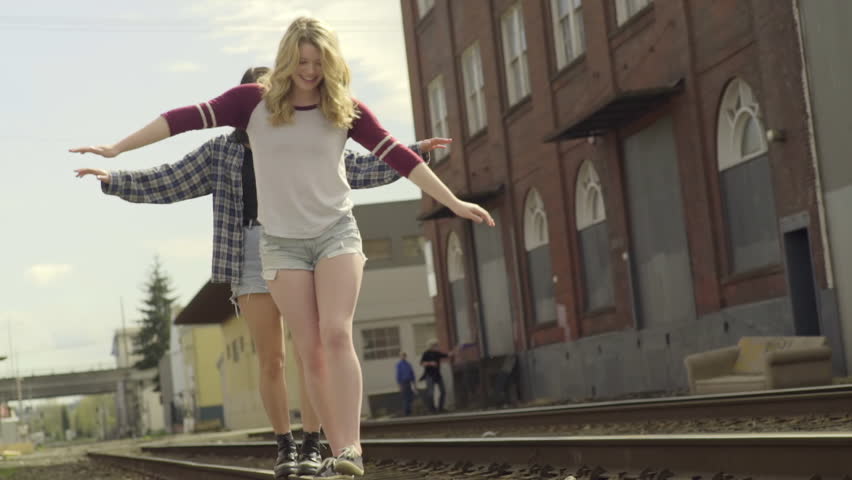 Two Friends Walk Along Train Tracks, Arms Outstretched, Balancing (Slow Motion)