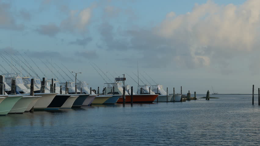 A fleet of charter fishing boats is docked under a late afternoon sky at the marina of the Oregon Inlet Fishing Center in Nags Head, North Carolina in the Outer Banks.