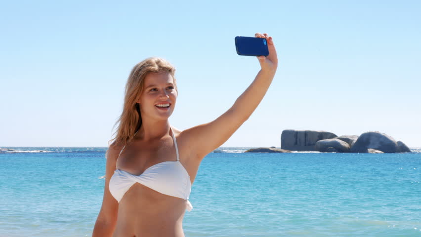 Beautiful blonde taking selfie on beach in ultra hd format