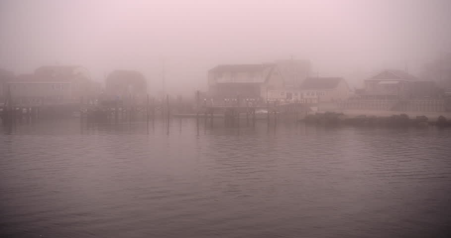 New England fishing village harbor in gloomy fog.  Water flowing and seagulls flying.